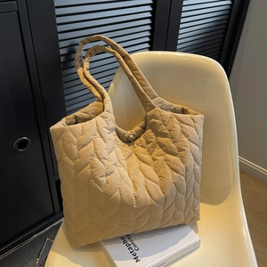 Minimalist beige quilted tote bag in nylon with leaf pattern on a modern chair