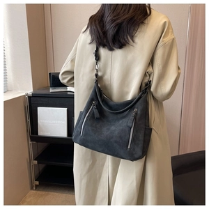 Model wearing a large dark grey matte leather tote bag with silver decorative zippers