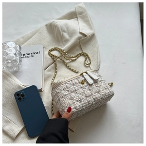 Dettaglio borsa a tracolla in tweed con catena dorata e ciondoli a fiore sulla zip