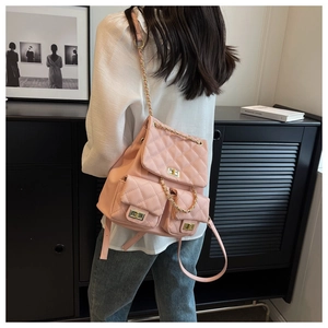 Detail of pink quilted backpack featuring gold chain straps and metal turn-lock closures
