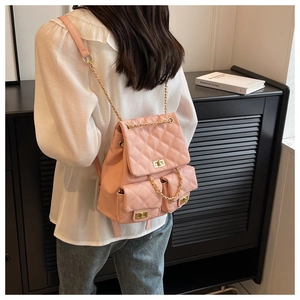 Pink quilted backpack with golden chain straps shown on a model's back view