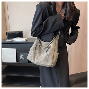 Detail of grey vintage tote bag with dual zippers worn by a model in a stylish indoor setting