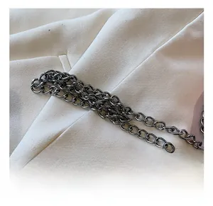Detailed close-up of polished gunmetal chain strap on white twill fabric bag