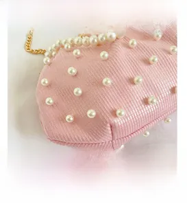 Gros plan du sac à main en tissu rose avec perles blanches et chaîne dorée élégante