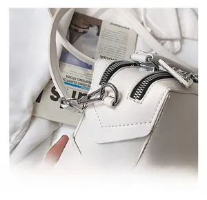 Close-up of white lychee pattern leather bag with silver metal hooks and black zipper details