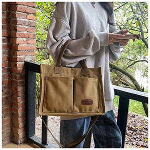 Detailed shot of brown canvas tote bag with front pockets and adjustable shoulder strap