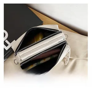 Detail view of the multi-layer interior compartments and metallic zippers of the beige bag