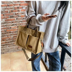 Outdoor shot of khaki canvas tote bag featuring double front pockets and leather label