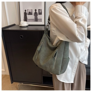 Detail view of a vintage dark green shoulder bag featuring double vertical zip pockets