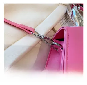 Detailed close-up of the silver metal hook and pink lychee leather texture of the bag