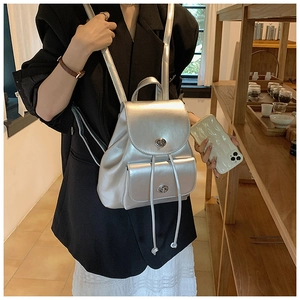 Detail of silver metallic backpack with twist-lock closure and adjustable drawstrings
