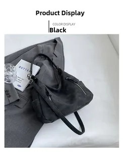 Detail of black matte suede Hobo bag with symmetrical silver zippers on a grey blazer