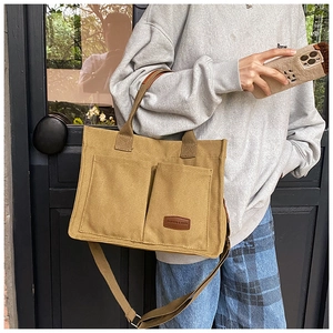 Detail view of khaki canvas tote bag with front pockets and fashion leather label