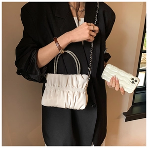 Close-up of elegant pleated cloud bag in off-white with sparkling rhinestone handle