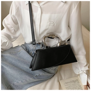 Detail of minimalist black crossbody bag with unique silver irregular metallic handle