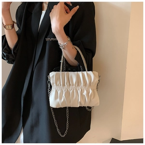 Detail of white pleated cloud bag with rhinestone handle and silver metal chain strap