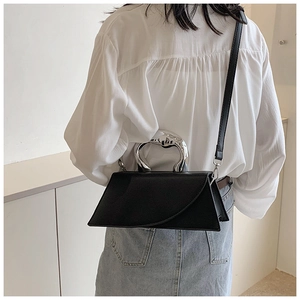 Close-up of minimalist black leather crossbody bag with unique silver metallic handle