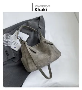 Detail view of khaki matte leather hobo bag on grey suit jacket with styling props