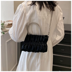 Detail of black pleated cloud bag with sparkling rhinestone handles and silver chain strap