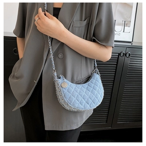 Detail of light blue denim crescent bag with quilted pattern and rose metal pendant