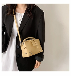 Close-up of cream crossbody bag featuring silver stud accents and dual zipper closure