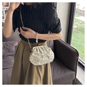 Gros plan du sac à main crème orné de perles avec chaîne dorée et fermoir
