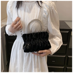 Close-up of sparkling rhinestone handle on black pleated cloud evening bag