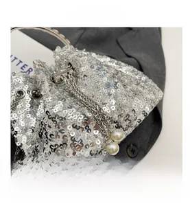 Detail of silver sequin bucket bag with metal ring handle and pearl chain drawstring