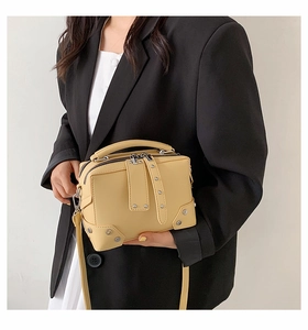 Chic beige rivets leather square crossbody bag worn by model on a minimalist background