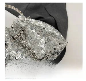 Macro view of silver sequin bucket bag with ring handle and elegant pearl charm detail