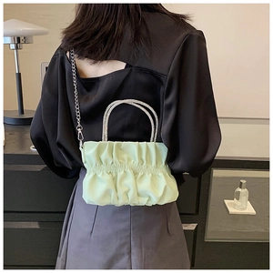 Model view of a light green pleated cloud bag with rhinestone handle and chain strap