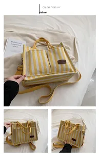 Detail of yellow and white striped canvas tote bag with front pockets and leather tag