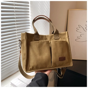 Detail showing khaki canvas tote with large pockets and brown leather wrapped handles