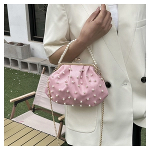 Sac nuage plissé rose avec perles et chaîne dorée, porté par un mannequin en extérieur