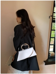 Artistic white leather handbag featuring a unique irregular folding design and silver handle
