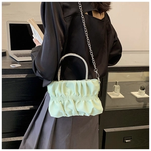 Detail of light green pleated cloud bag featuring rhinestone handle and silver chain strap