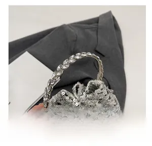 Detail of silver sequin bucket bag featuring a leaf-shaped rhinestone-studded metal handle