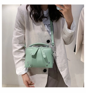 Detail of mint green crossbody bag with silver rivet studs and detachable long strap