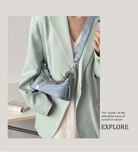 Détail du sac croissant en denim bleu clair avec chaîne argentée et large sangle