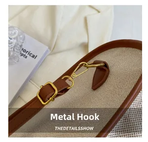 Detailed macro view of light gold metal hooks and adjustable buckle on canvas tote bag