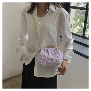 Détail du sac à main en velours côtelé violet clair avec perles blanches et fermoir doré