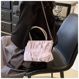 Macro detail of lavender pleated cloud bag with shimmering rhinestone handle and chain