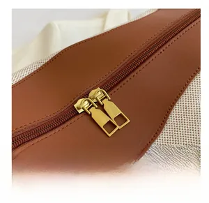 Detail shot of canvas and brown leather stitching with vintage gold double zipper closure