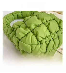 Macro detail of the bright green quilted texture and soft puffy handle of the cloud handbag