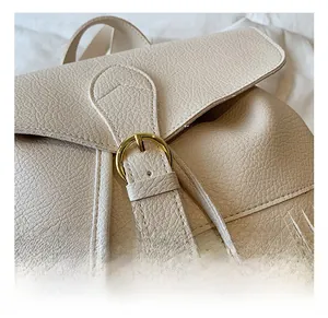 Détail d'un sac à dos en cuir litchi avec ferrures dorées et élégant pompon à franges