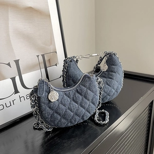 Quilted denim crescent crossbody bag with silver chain and camellia charm accessory