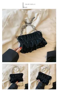 Detail of ruched black evening bag with rhinestone handle and metal chain strap