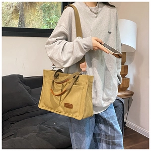 Detail of canvas tote bag with adjustable shoulder strap and front leather logo patch