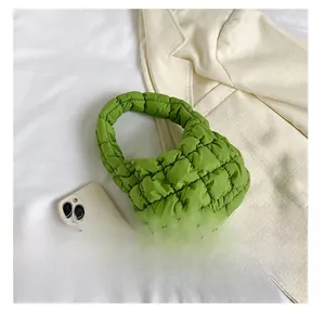 Close-up of a green quilted cloud handbag showing soft texture next to a smartphone