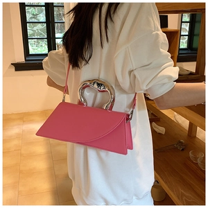 Close-up of pink geometric handbag featuring a silver wavy metal handle and crossbody strap